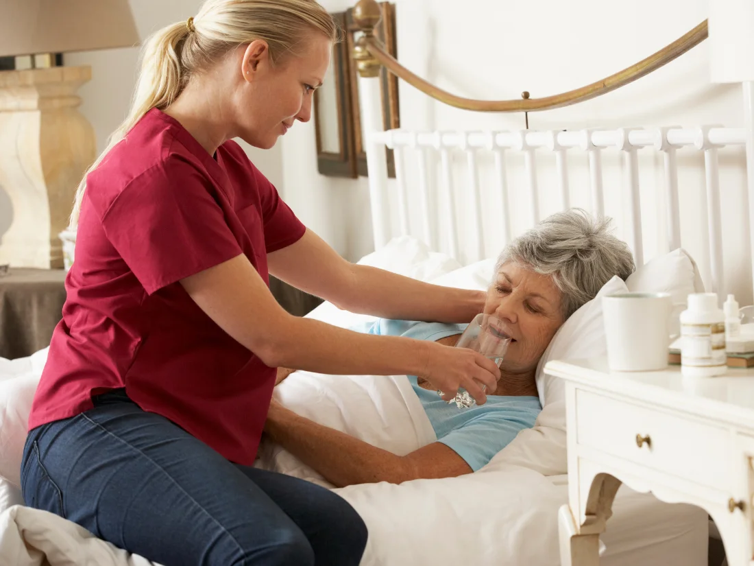 A compassionate home health aide providing attentive bedside care for a senior at home in Alexandria City, VA.